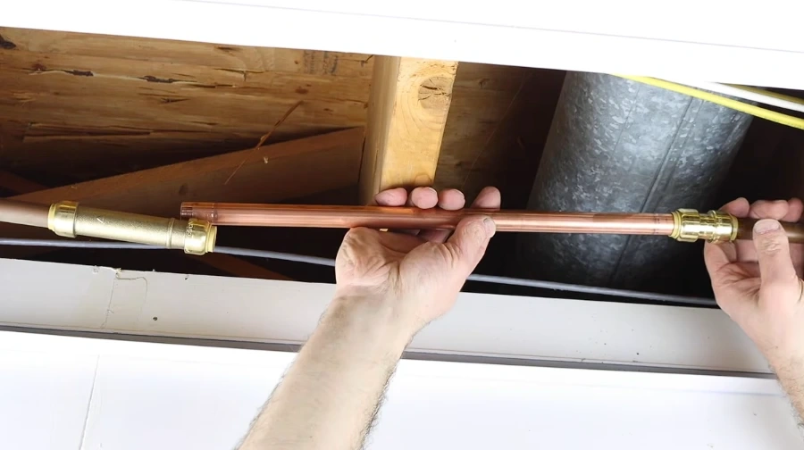 Hands fitting a new copper pipe section with push-fit connectors