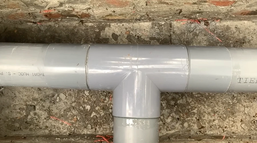 Newly installed PVC drain pipe fitting, clean and sealed, after repair
