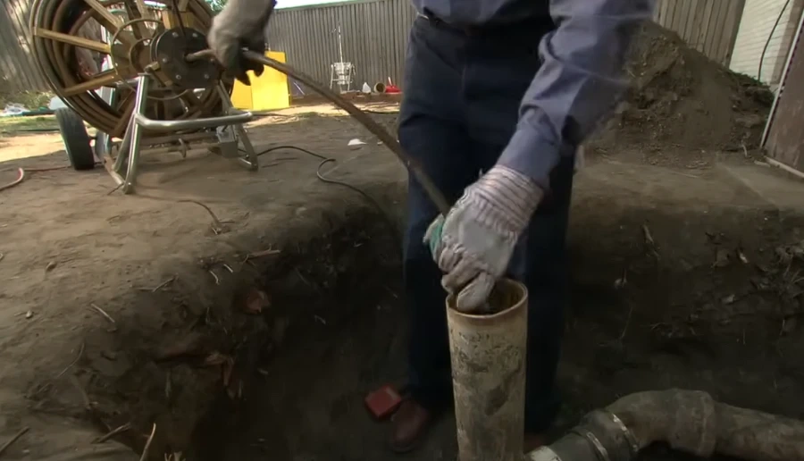 Plumber clearing a sewer line with a professional snaking machine