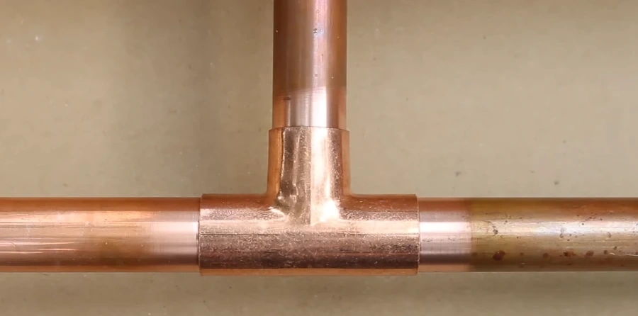 Plumber soldering a copper pipe elbow joint with a torch