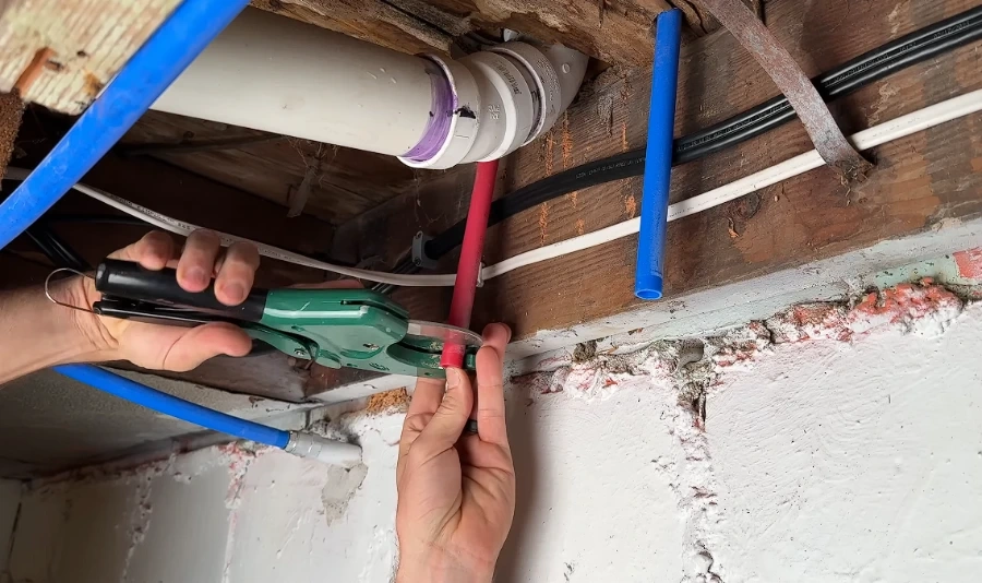 Plumber cutting red PEX pipe during a home repipe